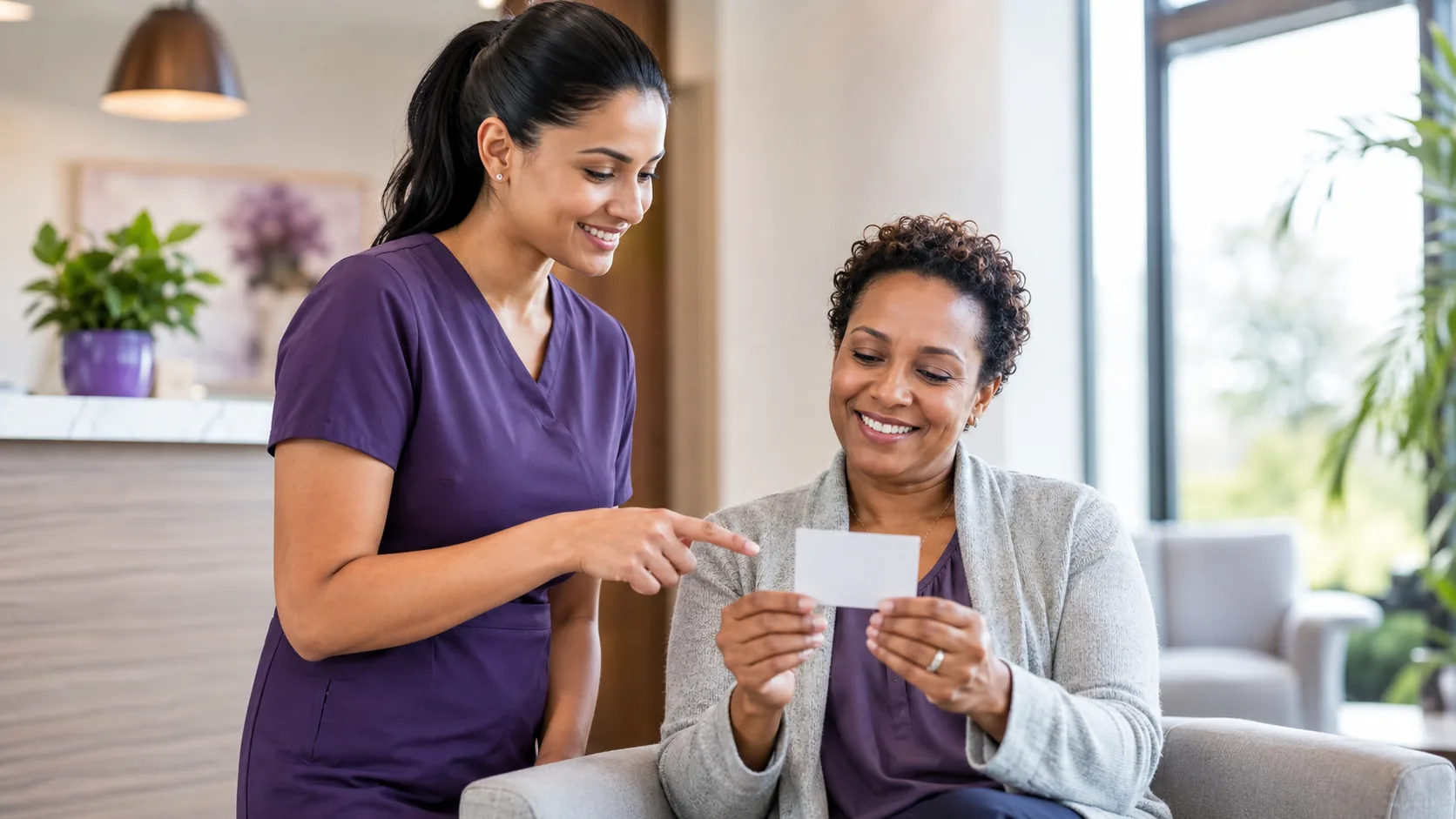 Practitioner at a bright clinic front desk helping a seated patient review her insurance card, conveying help understanding coverage