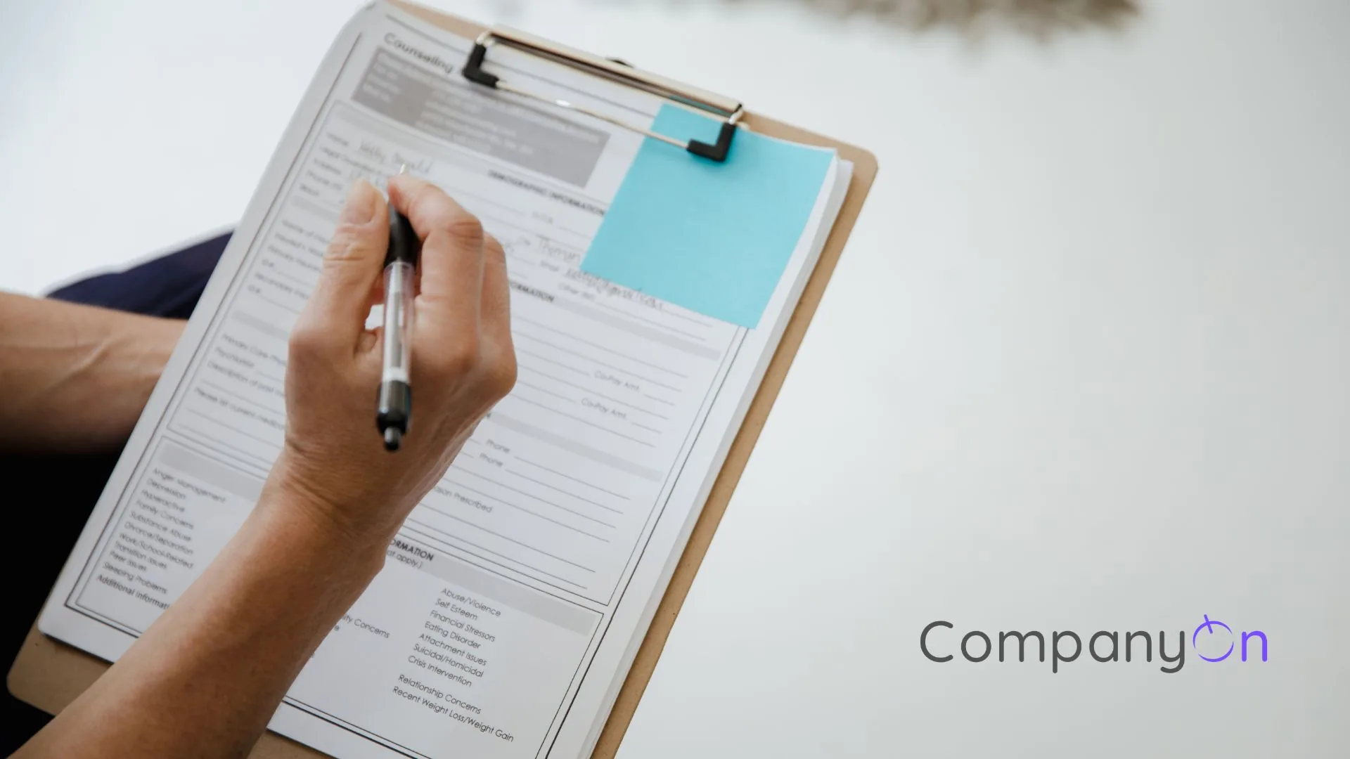 Clinician's hand completing a paper intake form on a clipboard, illustrating a practice audit checklist