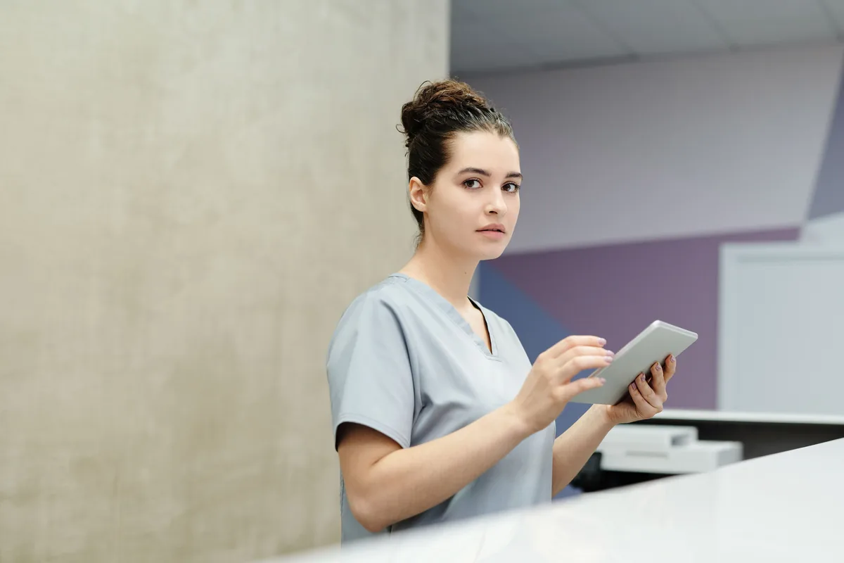 Independent clinician reviewing the day's appointment schedule on a tablet at the clinic front desk