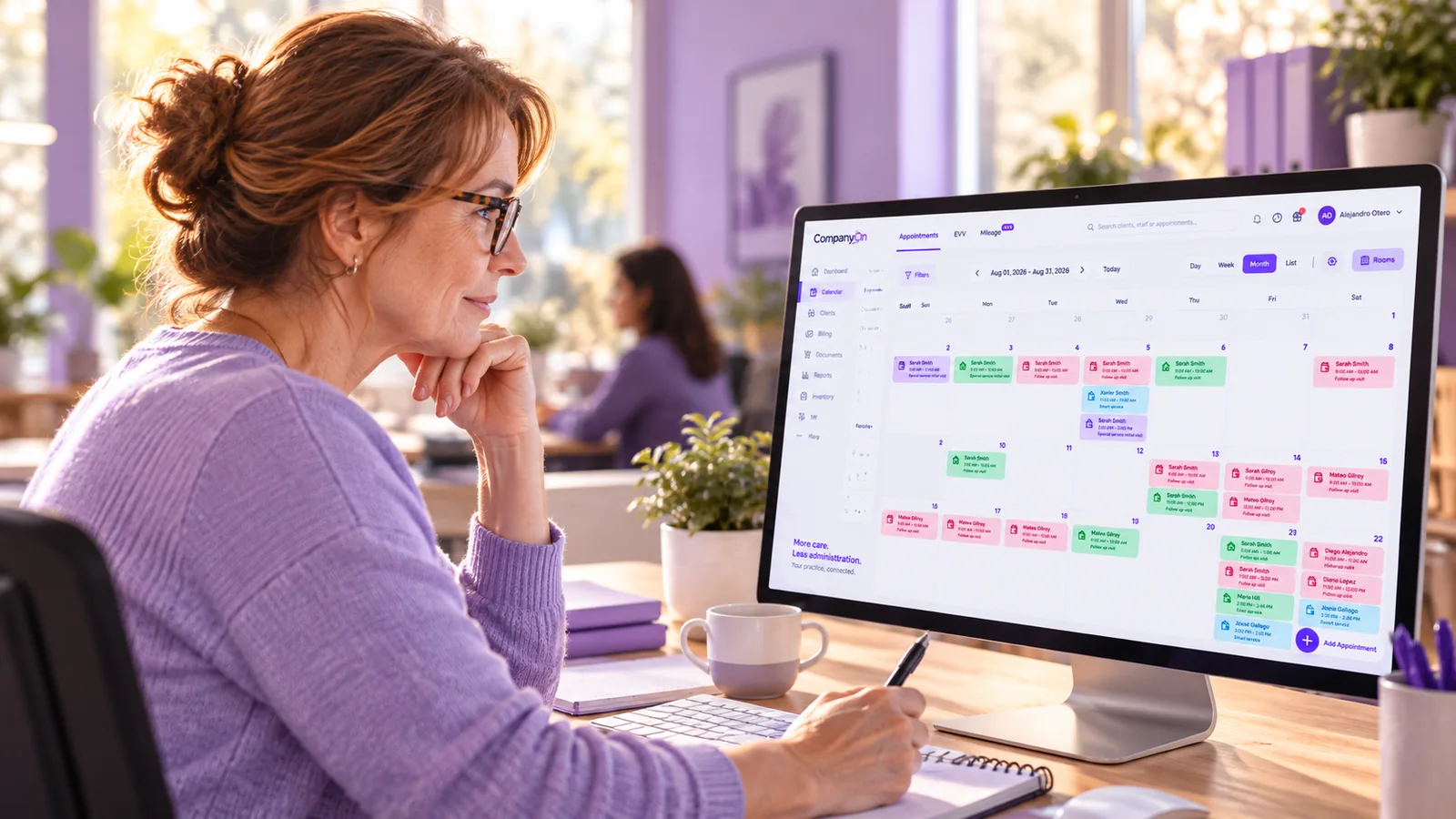 A home care scheduler calmly reviewing a dashboard with a missed visit alert on screen in a modern office
